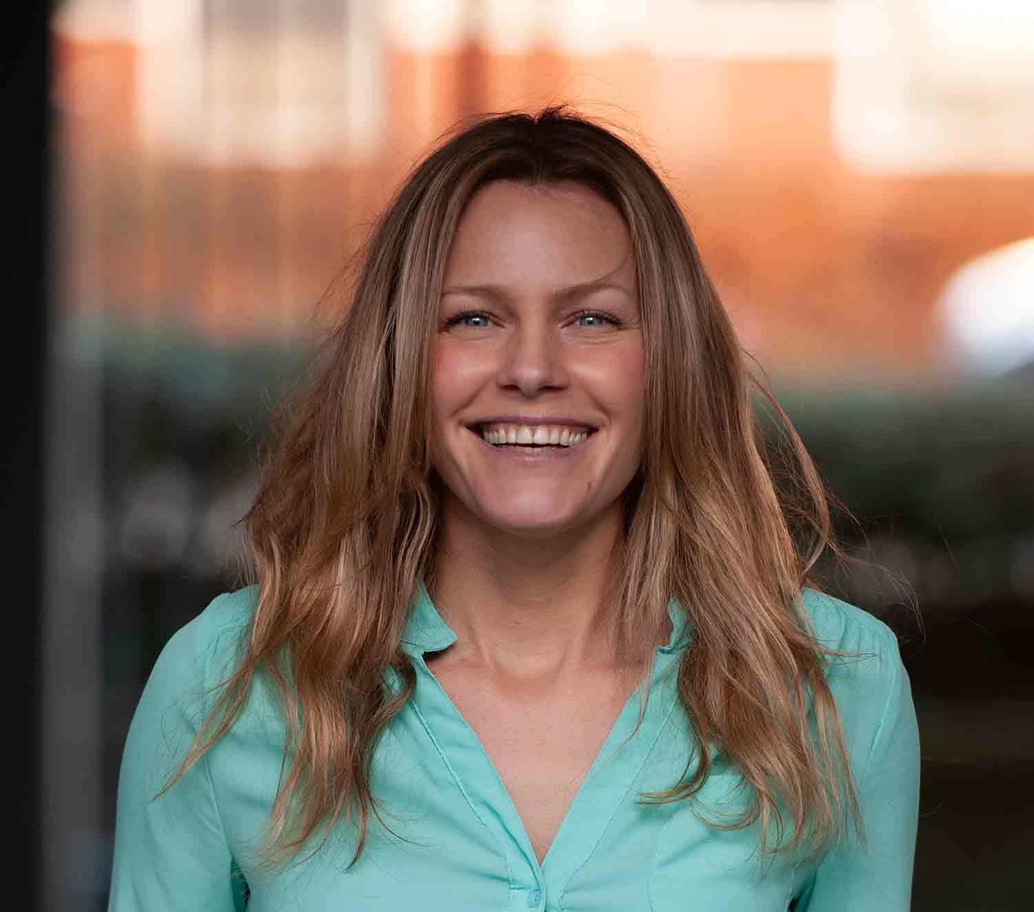 Portrait of Kathryn Ann Jankowski from shoulders up wearing a turquoise blouse and hair down taken by Hilde van der Sterren