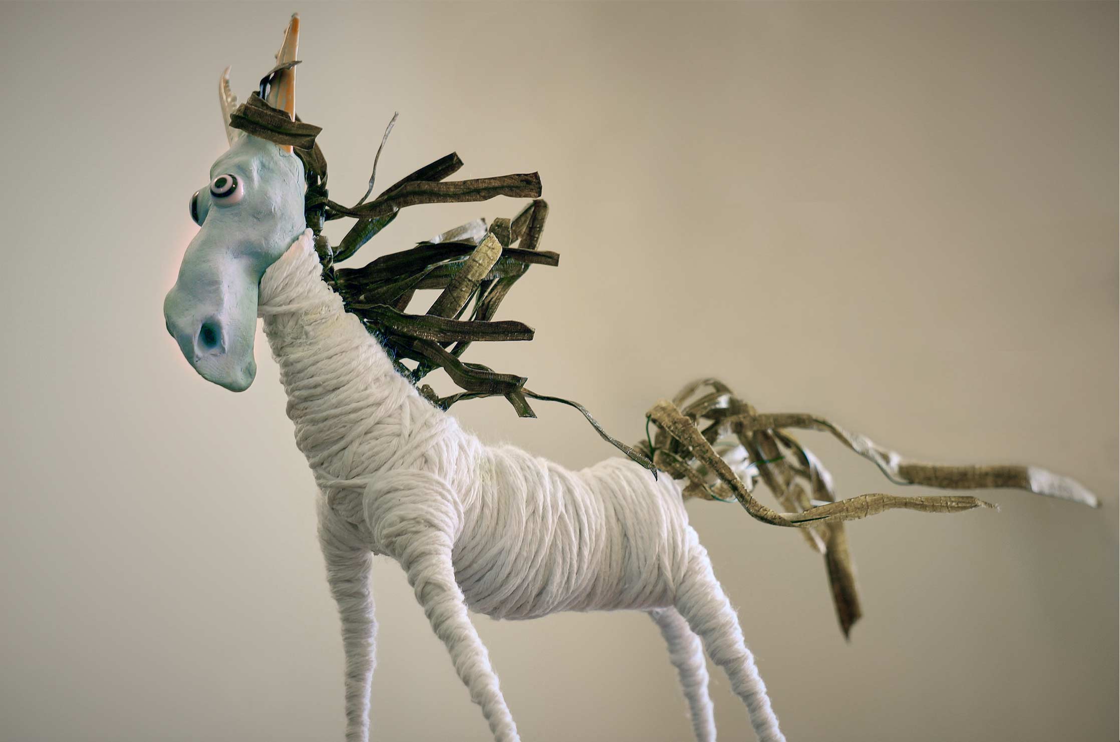 A stop motion horse character. His face and hooves are sculpted in blue air-dry clay and has a body of white cotton string.
